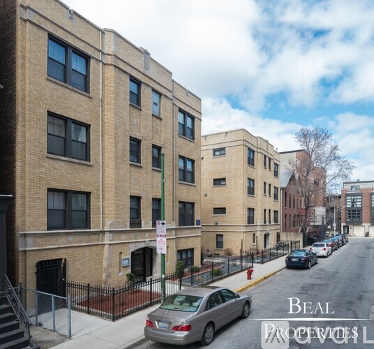 A street view of a residential area with apartment buildings and parked cars.