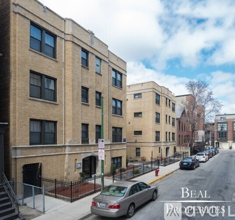 A street view of a residential area with apartment buildings and parked cars.