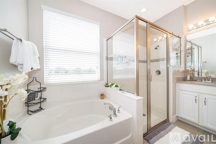 A white bathroom with a tub, sink, and mirror.