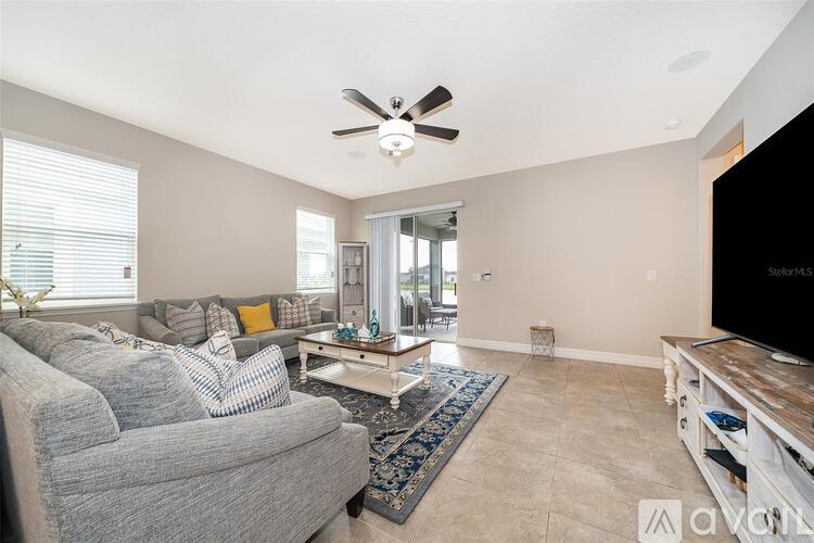 A living room with a grey couch and a ceiling fan.
