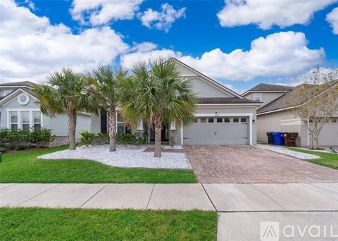 A house with a driveway and palm trees in front.