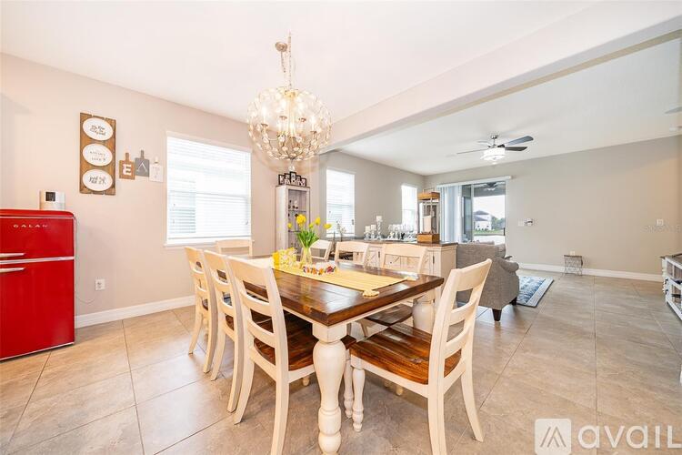 A dining room with a wooden table and chairs, a red fridge, and a chandelier.