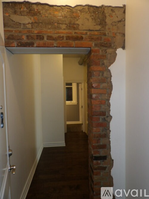A hallway with a brick wall and a door.