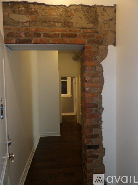 A hallway with a brick wall and a door.
