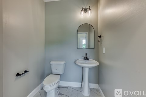 A bathroom with a toilet, sink, and mirror.
