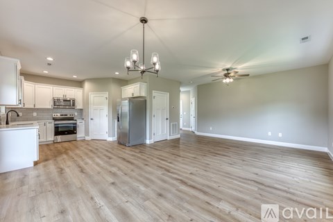 A spacious kitchen with white cabinets and a wooden floor.