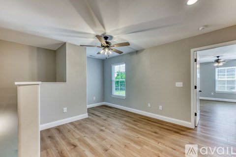 A room with a ceiling fan and wooden flooring.