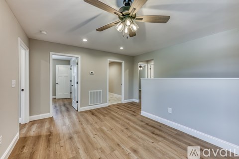 A spacious room with a ceiling fan and wooden flooring.