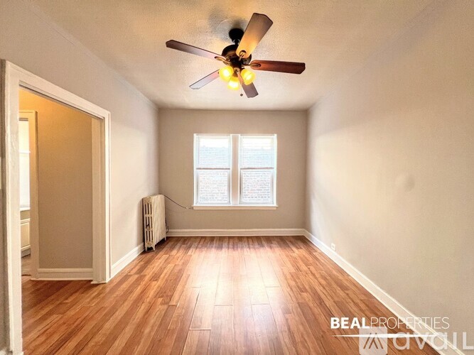 A room with a ceiling fan and a window with blinds.