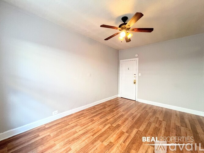 A room with a ceiling fan and wooden flooring.