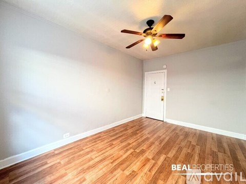 A room with a ceiling fan and wooden flooring.