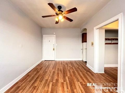A room with a ceiling fan and wooden flooring.