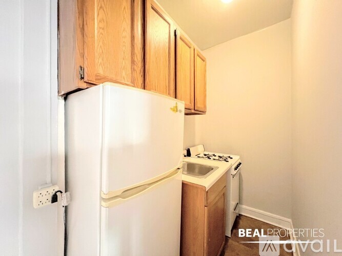A white refrigerator is in a kitchen with wooden cabinets.