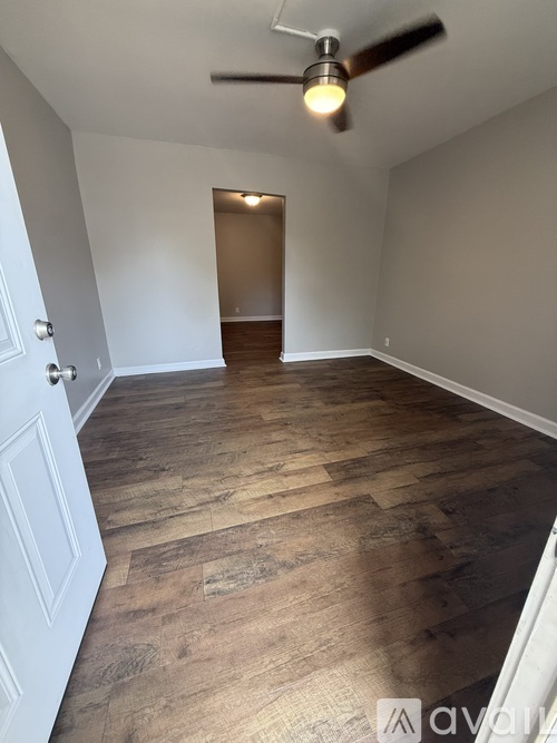A room with wooden flooring and a ceiling fan.