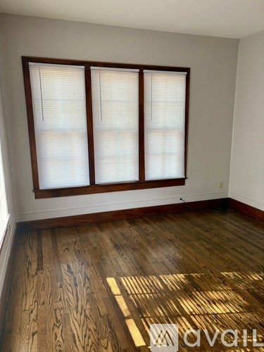 A room with wooden floors and a window with blinds.