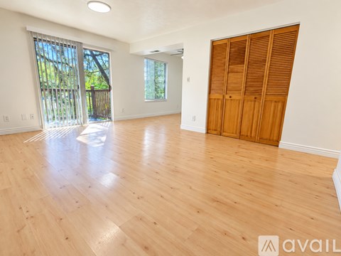 A room with wooden floors and a large window with blinds.