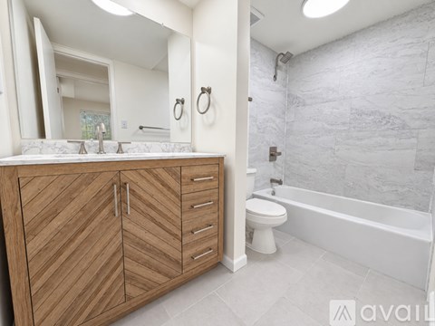 A bathroom with a wooden vanity and a white toilet.