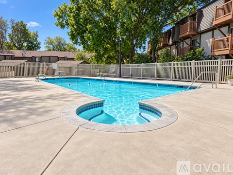 A round above ground pool with a concrete patio and a fence around the pool.
