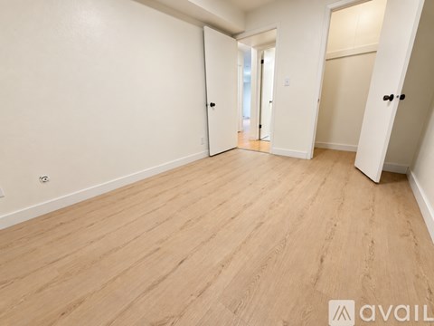 A spacious room with wooden flooring and white walls.