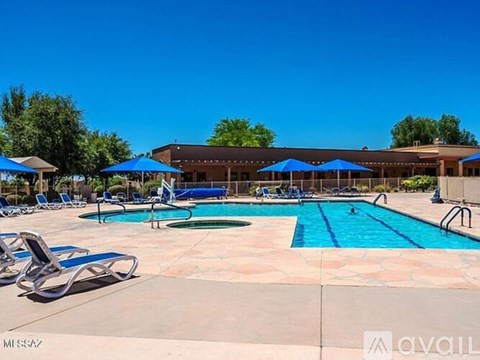 A large outdoor swimming pool with sun loungers and umbrellas.