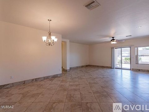 A spacious room with tiled flooring and a chandelier.