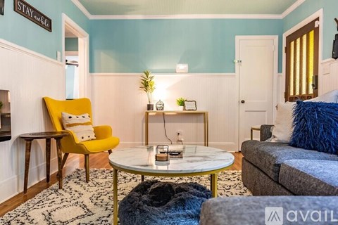 A living room with a yellow chair and a white coffee table.
