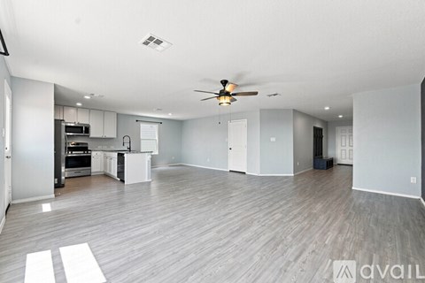 A spacious living room with a kitchen area in the background.