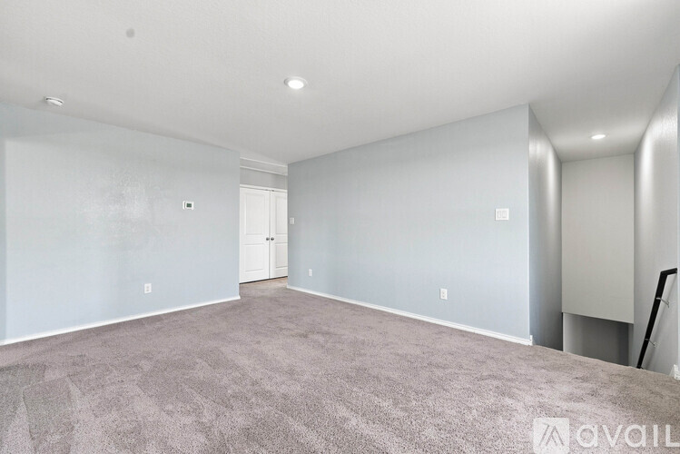 A spacious room with a carpeted floor and a white door.
