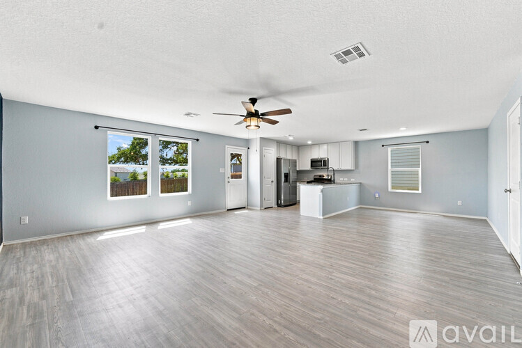 A spacious living room with a ceiling fan and sliding glass doors.