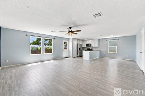 A spacious living room with a ceiling fan and sliding glass doors.