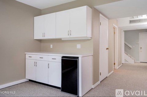 A kitchen area with white cabinets and a black dishwasher.