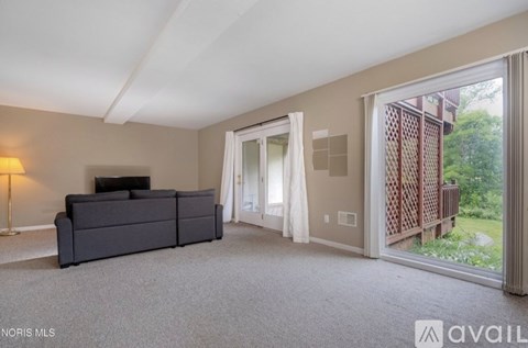 A living room with a grey sofa and a large window with curtains.