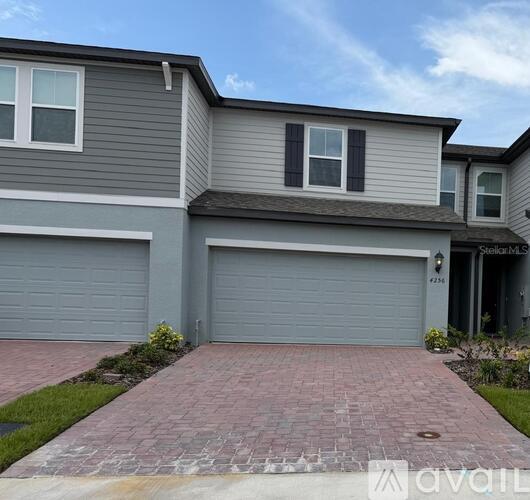 A two-story house with a garage and a brick driveway.