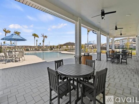 A patio with a table and chairs overlooking a pool.