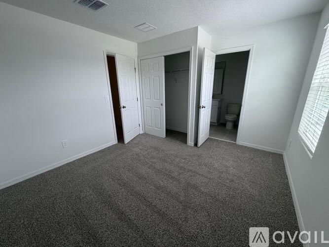 A carpeted room with a door and a window.