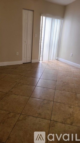 A room with tiled flooring and a door leading to a window.