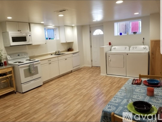 A kitchen with white appliances and wooden floors.