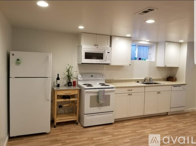 A kitchen with white appliances and wooden floors.