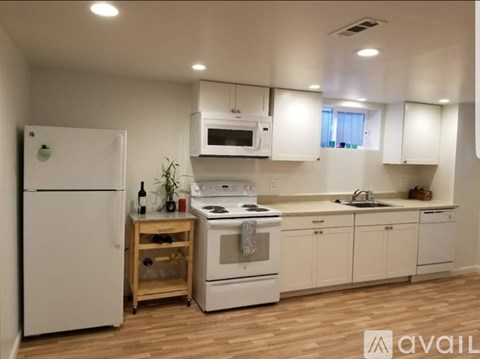 A kitchen with white appliances and wooden floors.