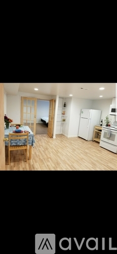 A kitchen with a refrigerator, a dining table with chairs, and a window.