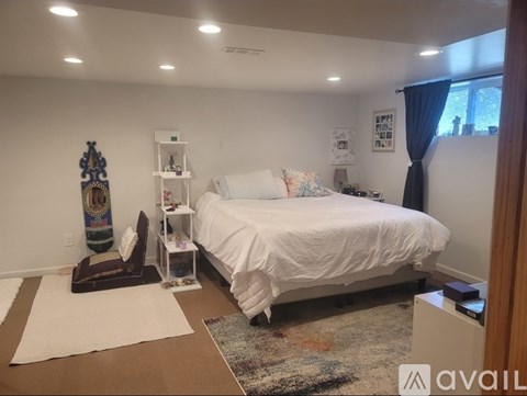 A bedroom with a white bed and a decorative vase on the floor.