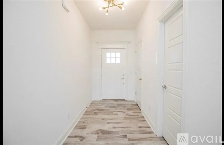 A hallway with a tiled floor and a chandelier.
