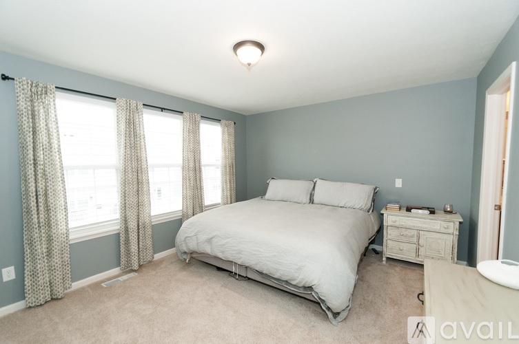 A bedroom with a bed, nightstand, and window with curtains.