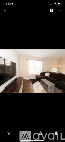 A living room with a dark brown couch and a wooden floor.