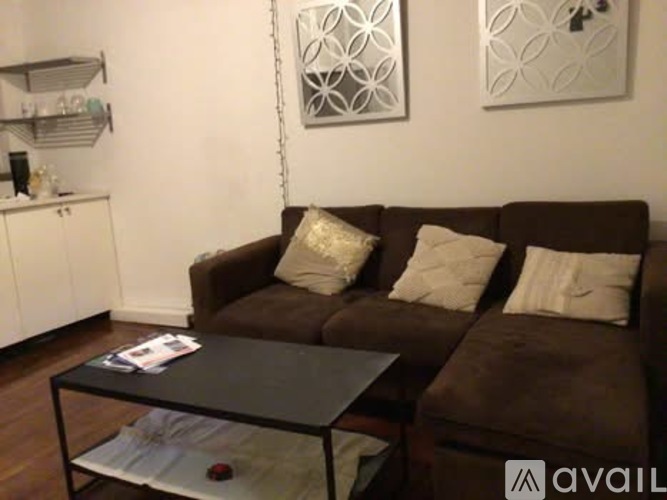 A brown couch with a glass table in front of it.