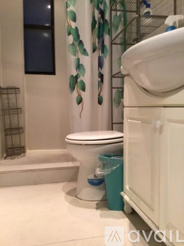 A white toilet with a blue bucket next to it in a bathroom.
