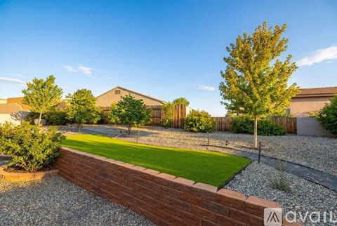 A backyard with a gravel path, a grassy area, and a wooden fence.
