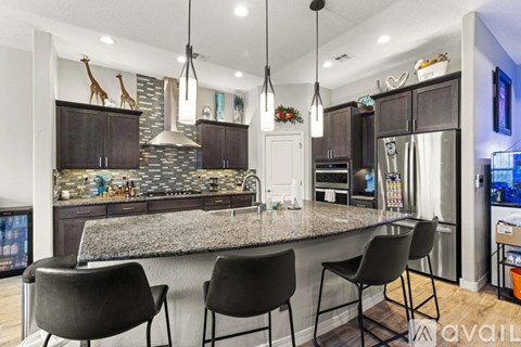 A kitchen with a granite countertop and black chairs.