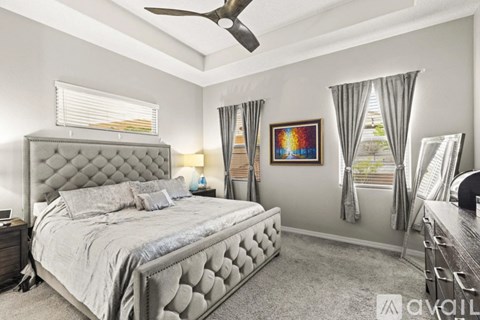 A bedroom with a large bed and a ceiling fan.