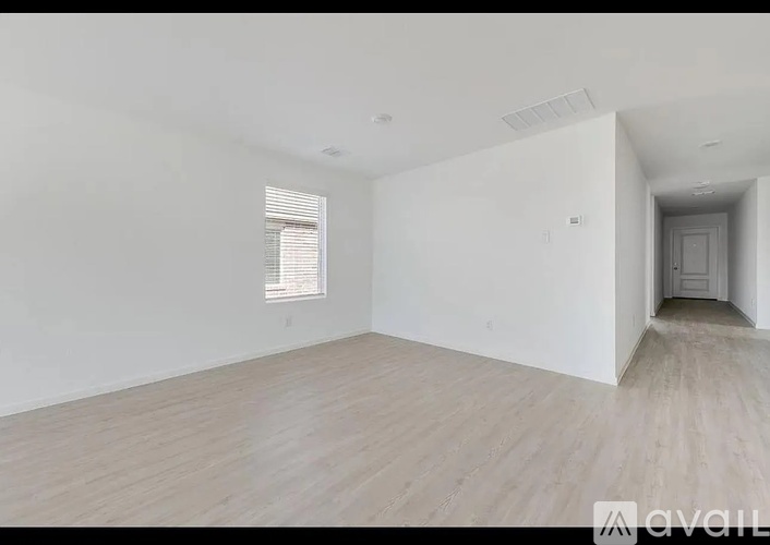 A spacious room with wooden flooring and white walls.